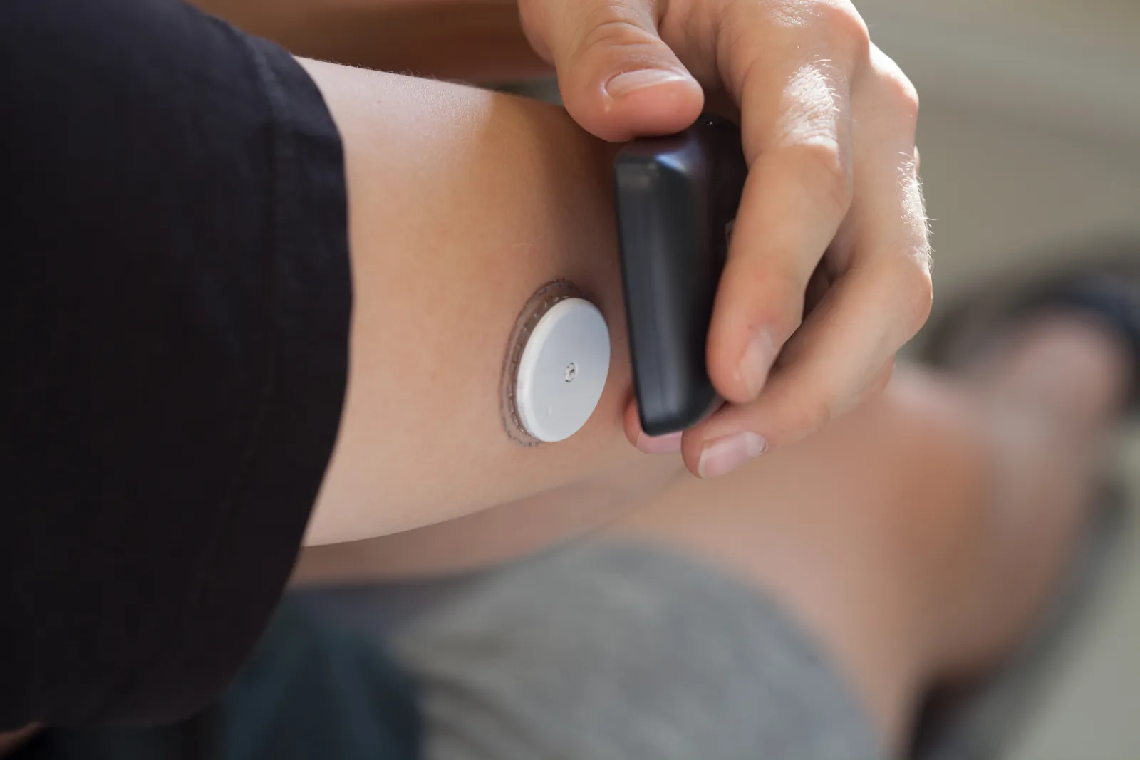 A glucose sensor on the upper arm being scanned with a reader